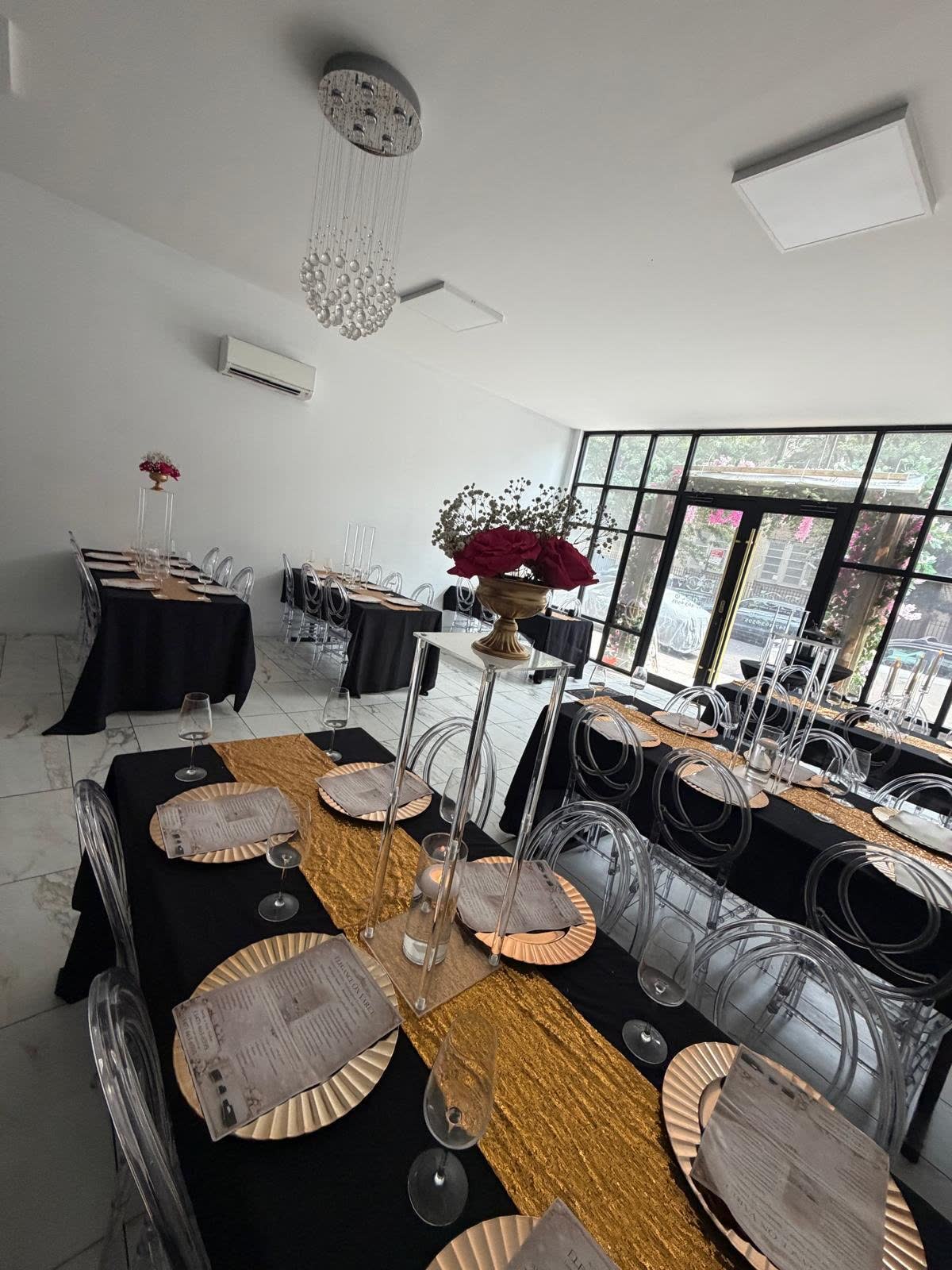 Black and gold gala tables arranged beneath chandeliers at Elegance on Varet