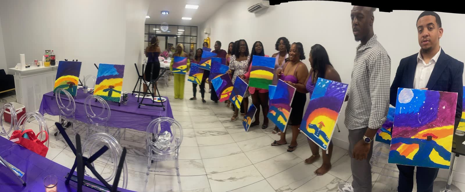 Paint and sip workshop guests holding colorful canvases at Elegance on Varet