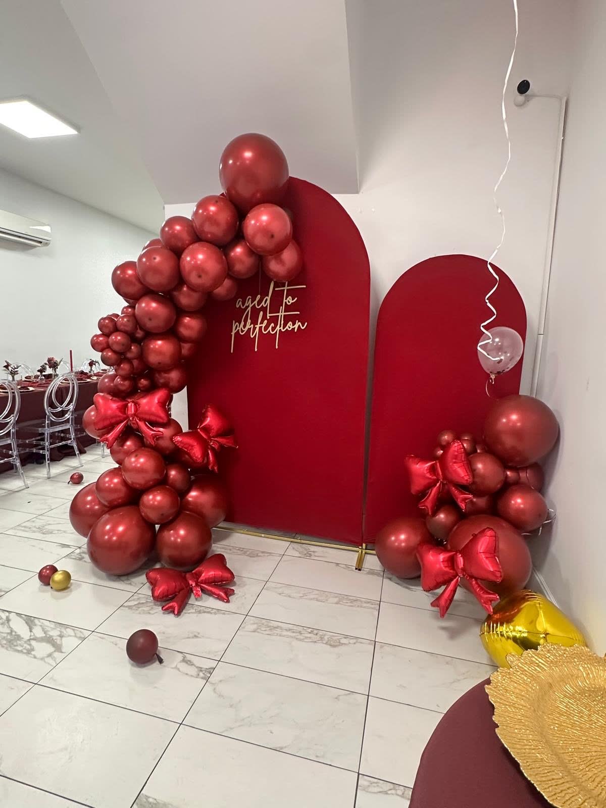 Bold red balloon celebration arch and gold table setting at Elegance on Varet